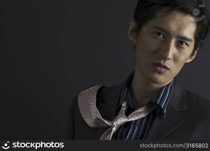 A serious-looking asian model flicks his tie over his shoulder