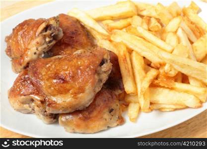 A serving dish piled with roast lemon chicken thighs and French fries, or chips