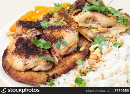 A serving plate of Lebanese sumac chicken thighs, cooked with sliced onions on Arab flat bread and served on a bed of rice and nuts, all garnished with coriander (cilantro) leaves