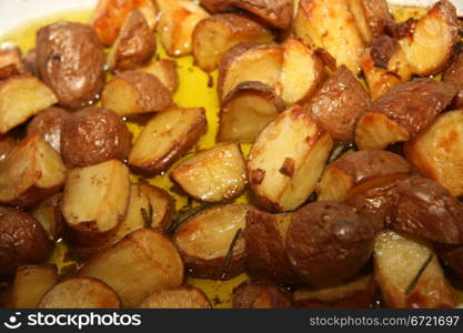 A serving plate with crispy backed potatoes in oil