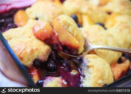 A serving spoon of fresh fruit cobbler with cinnamon