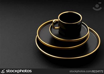 A set of black and golden ceramic plates and cup on a black background. Set of black and golden ceramic plates and cup on a black background