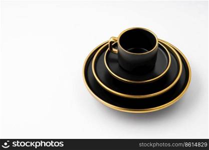A set of black and golden ceramic plates and cup on a white background. Set of black and golden ceramic plates and cup on a white background