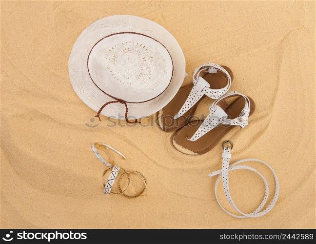 a set of bright summer clothes for the beach on the golden sand. the concept of the summer season and recreation. top view. beachwear in the sand