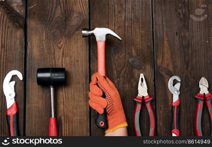 A set of construction tools on a brown wooden background, top view. Hammer, pliers, adjustable wrench