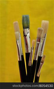 A set of paintbrushes isolated against a yellow background