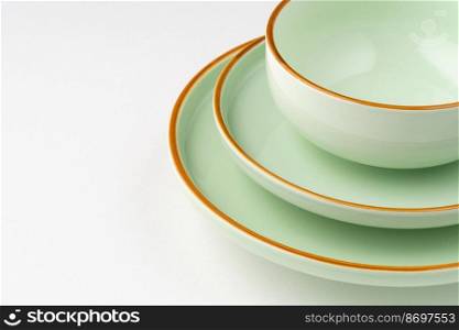 A set of pastel green ceramic tableware with orange outlines. Close-up. Set of pastel green ceramic tableware with orange outlines