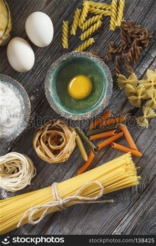 A set of raw pasta and addons on wooden table. A set of raw pasta and addons on wooden table. Studio picture
