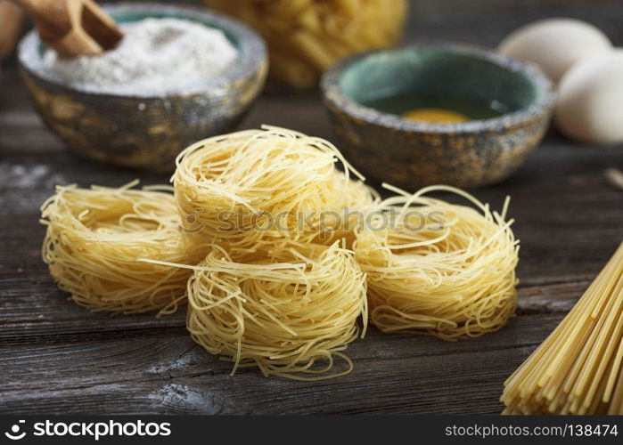 A set of raw pasta and addons on wooden table. A set of raw pasta and addons on wooden table. Studio picture