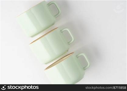 A set of white and pastel green ceramic teacups with orange outlines. Set of white and pastel green ceramic teacups with orange outlines