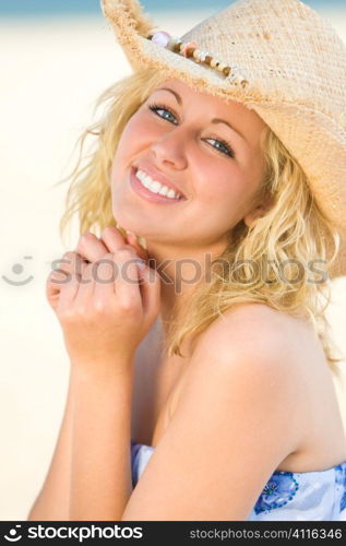 A sexy and beautiful young blond woman laughing at the beach with golden sand behind her