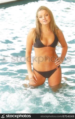 A sexy model poses in the water wearing a bikini showing off her cleavage.