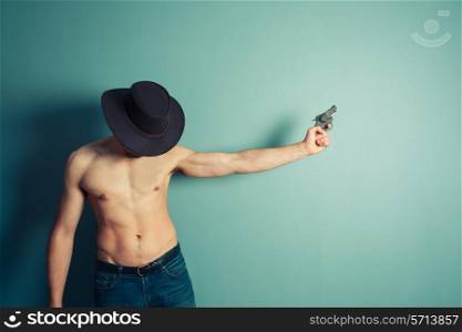 A sexy shirtless cowboy is pointing a revolver