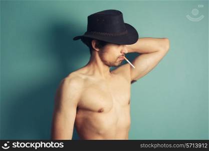 A sexy shirtless young cowboy is smoking a cigarette