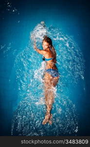 A sexy tanned lady in a colorful bikini posing in a swimming pool.