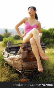 A sexy young Chinese model wears pink and poses by the sea.