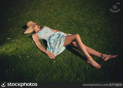 A sexy young woman is lying on the grass in a park and relaxing