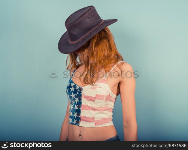 A sexy young woman is wearing a stars and stripes top and a cowboy hat