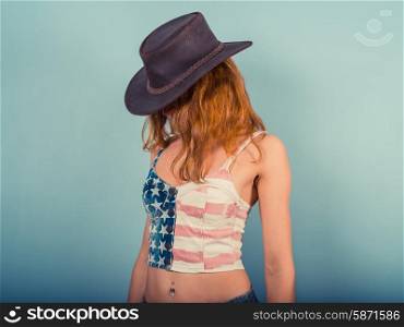 A sexy young woman is wearing a stars and stripes top and a cowboy hat