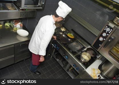 A shef behind the stove, preparing dinner in a professional kitchen