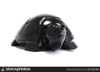 A shiny black stone turtle on a white background