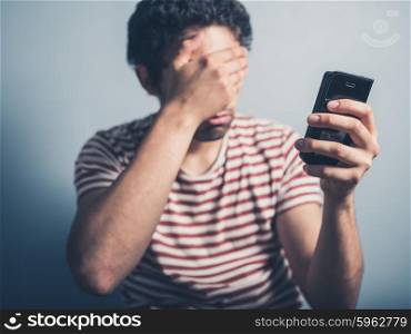 A shocked young man is using a smart phone
