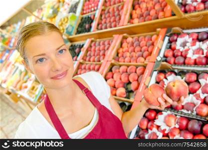 a shop assistant holding nectarines