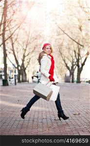 A shopping caucasian woman carrying shopping bags at an outdoor shopping mall
