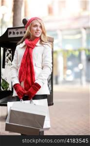 A shopping caucasian woman carrying shopping bags at an outdoor shopping mall