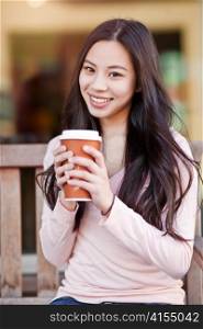 A shot of a beautiful asian woman drinking coffee outdoor