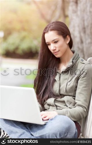 A shot of a beautiful ethnic college student working on her laptop on campus
