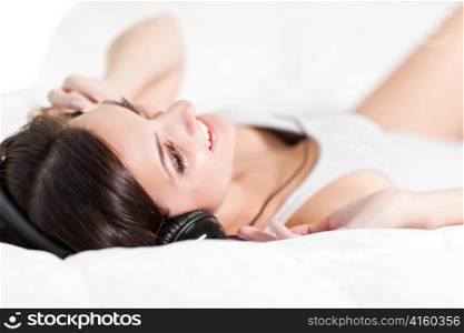 A shot of a beautiful girl lying down on the bed listening to music