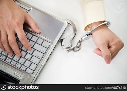 A shot of a businessman handcuffed on laptop