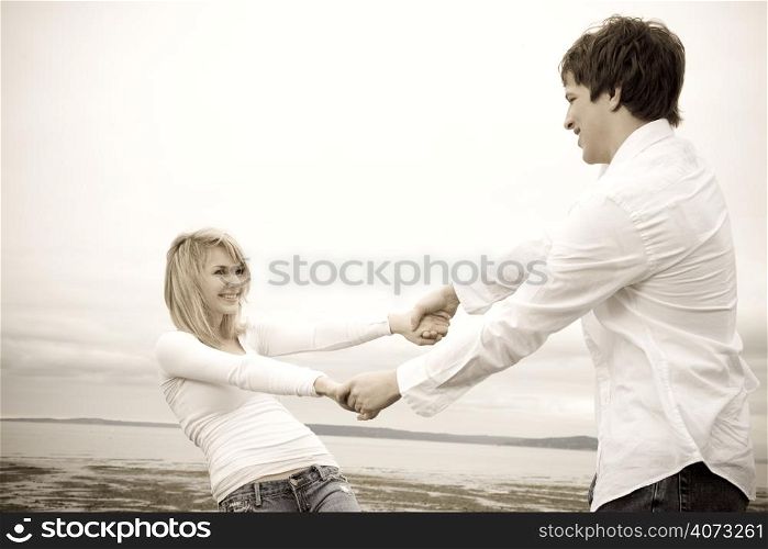 A shot of a caucasian couple having fun on the beach in sepia