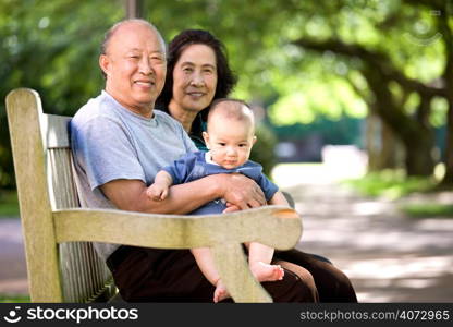 A shot of a cute asian child with his grandparents in a park