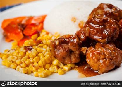 A shot of a delicious meatball and corn dish on rice dish