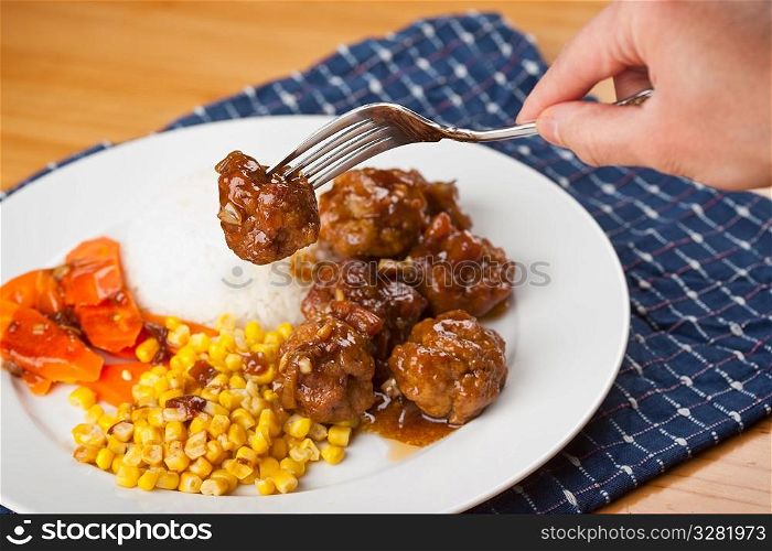 A shot of a delicious meatball and corn dish on rice dish