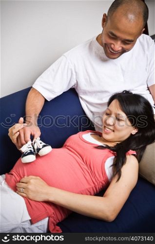 A shot of a father and mother playing with her unborn baby&acute;s shoes