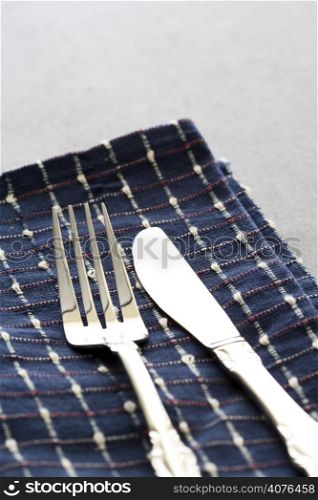 A shot of a fork and a spoon on a table cloth