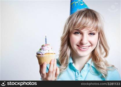 A shot of a girl celebrating her birthday holding a cupcake