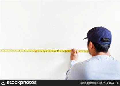 A shot of a man using measurement tape for home improvement