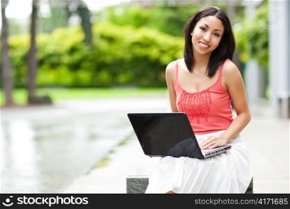 A shot of a mixed race woman talking on the phone and working on her laptop