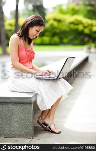 A shot of a mixed race woman talking on the phone and working on her laptop