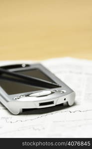 A shot of a PDA and financial chart on the newspaper