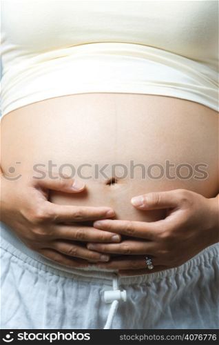A shot of a pregnant woman holding her stomach caressing her unborn child