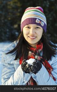 A shot of a woman holding a snowball during winter