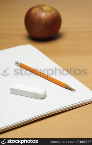 A shot of an apple, a blank notepad, an eraser and a pencil, can be used as education concept