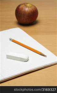 A shot of an apple, a blank notepad, an eraser and a pencil, can be used as education concept