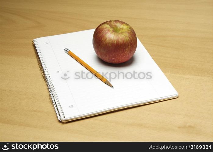 A shot of an apple and a blank notepad and a pencil, can be used as education concept