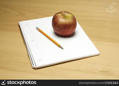 A shot of an apple and a blank notepad and a pencil, can be used as education concept